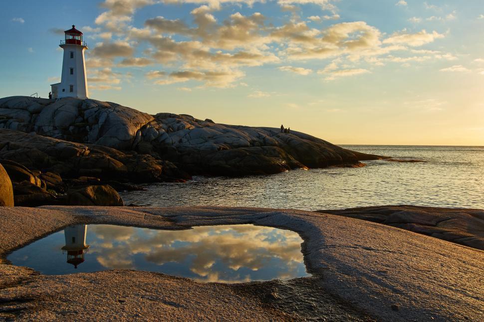 Free Image of Lighthouse at sunset reflects in ocean tide pool 