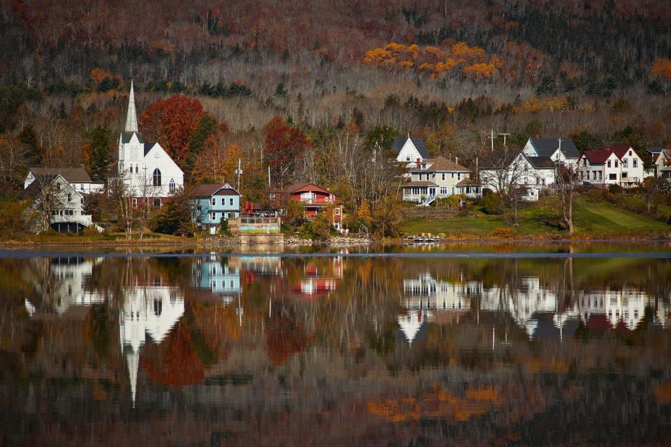 Free Image of Lakeside village reflects autumn colors in tranquil water 