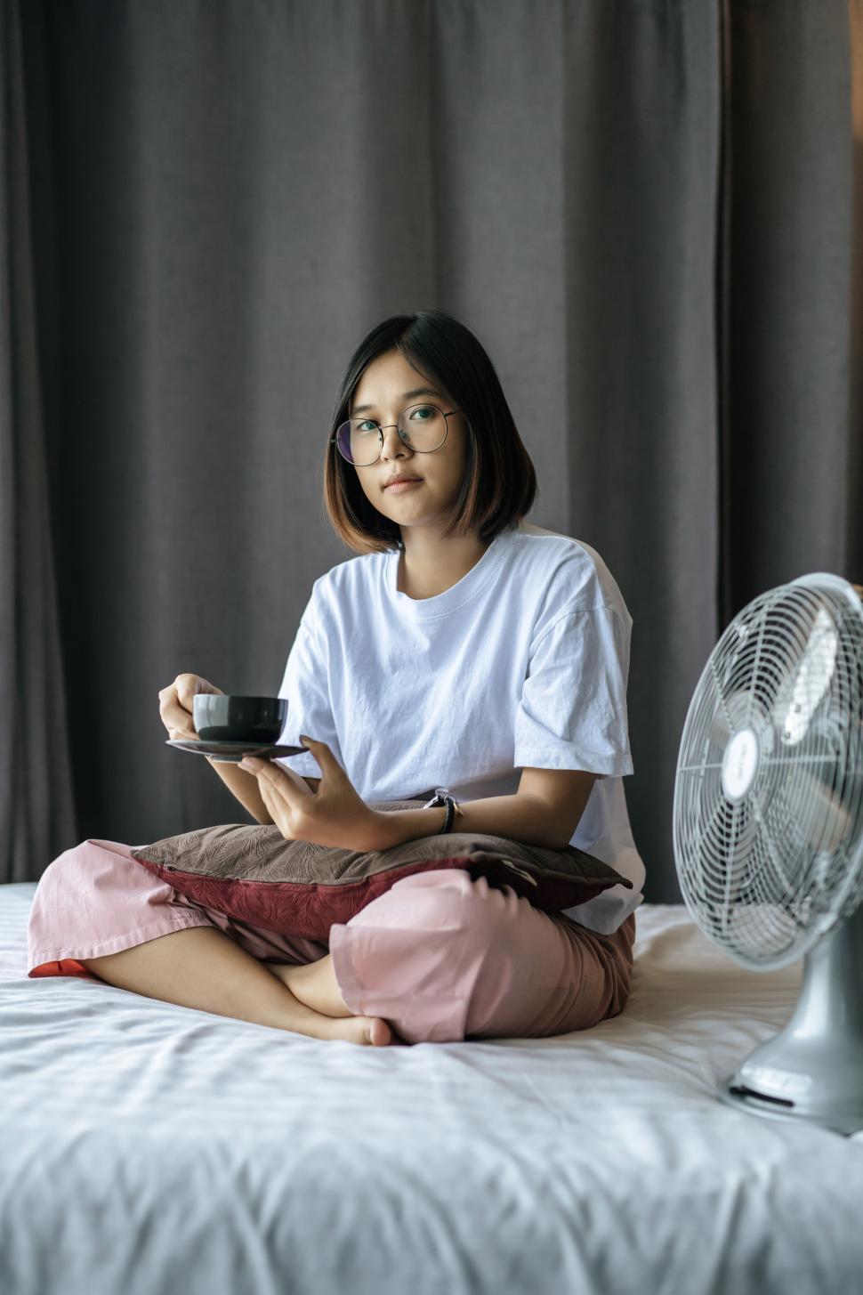 Free Image of A girl sitting and drinking coffee on the bedroom. 