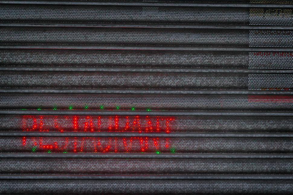 Free Image of City restaurant with closed shutters featuring neon lights at night 
