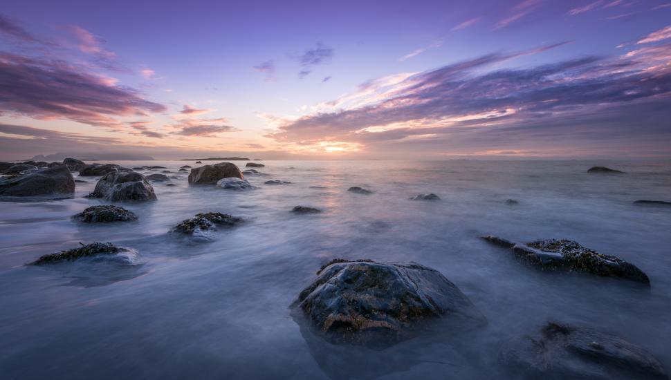 Free Image of Calm ocean waves gently flowing over rocky shore at sunset 