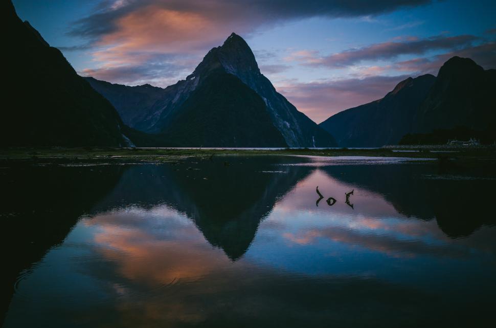 Free Image of Misty mountains reflect in tranquil water at dawn in New Zealand 