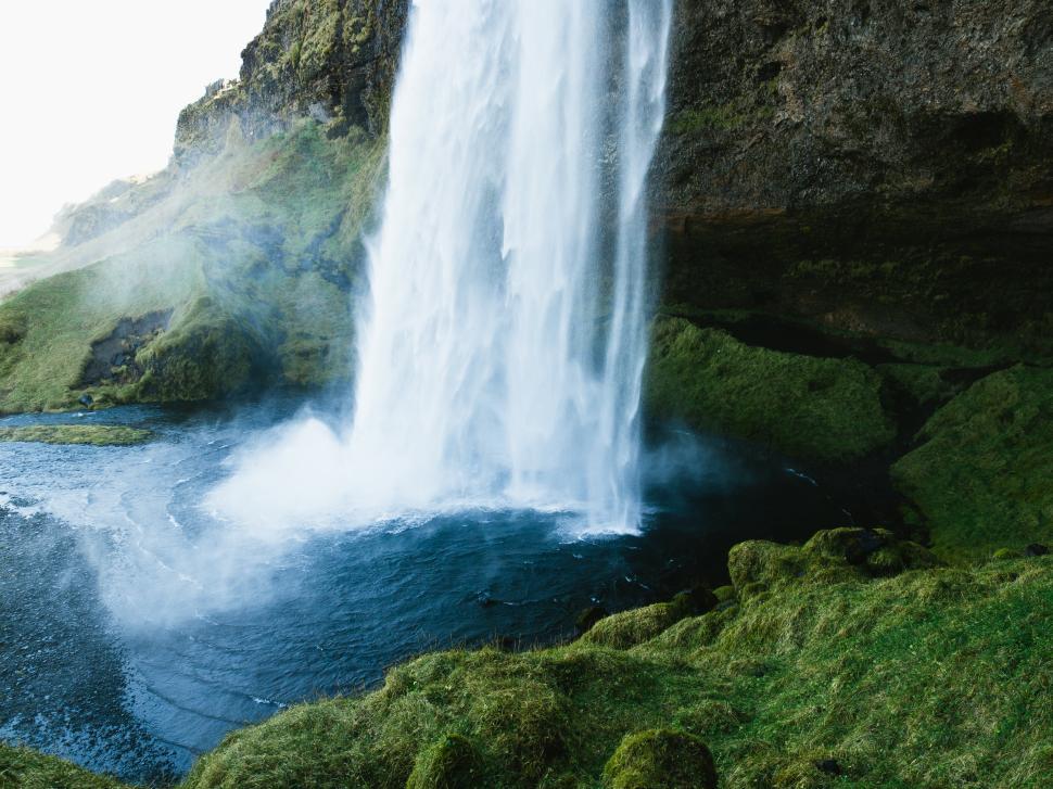 Free Image of Majestic waterfall cascades over rocky cliff near scenic green landscape 