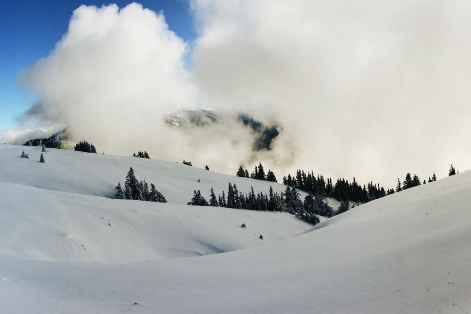 Free Image of Snow-covered mountains reveal hidden valleys under clouds 