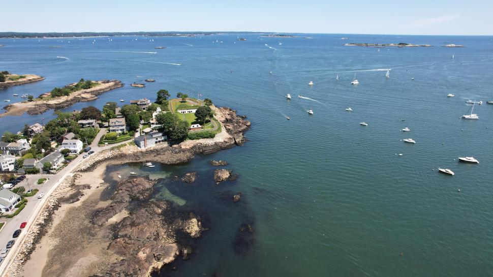 Free Image of Scenic coastal view featuring boats and rocky shoreline at noon 