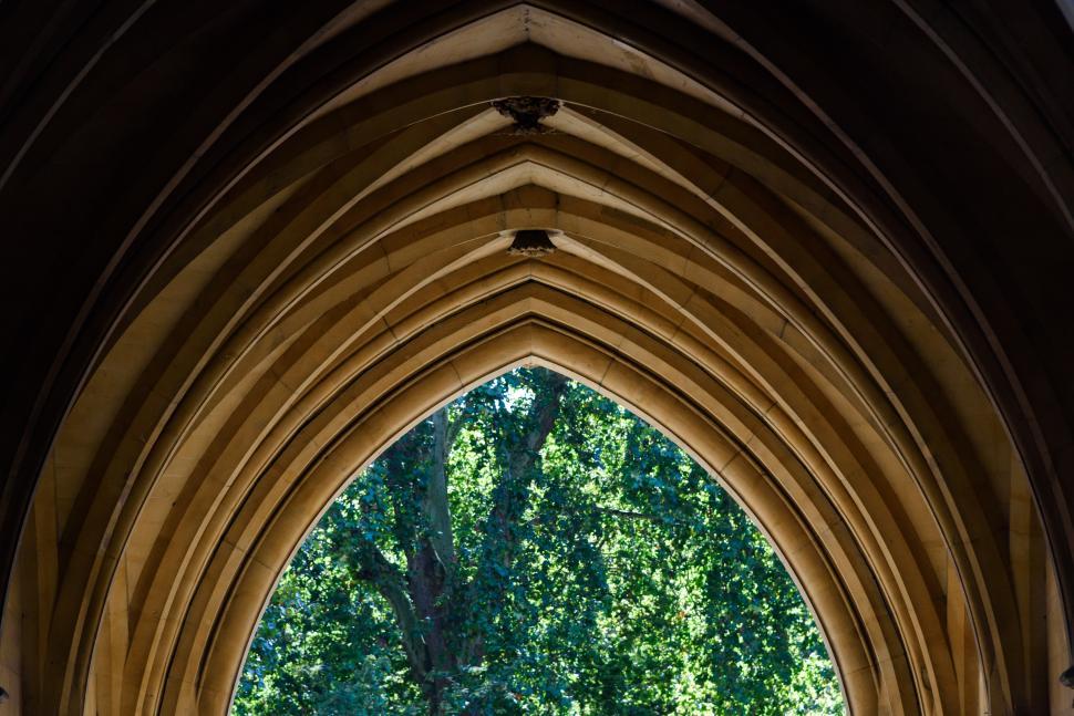 Free Image of Arching stone structure framed by vibrant greenery 