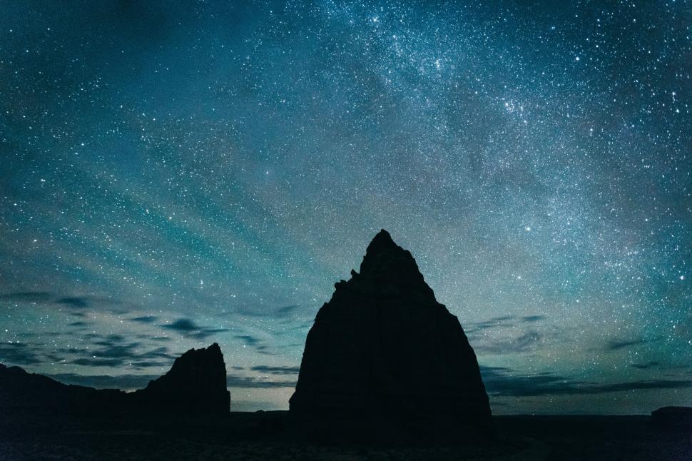 Free Image of Starlit night sky over towering rock formations in a remote desert 