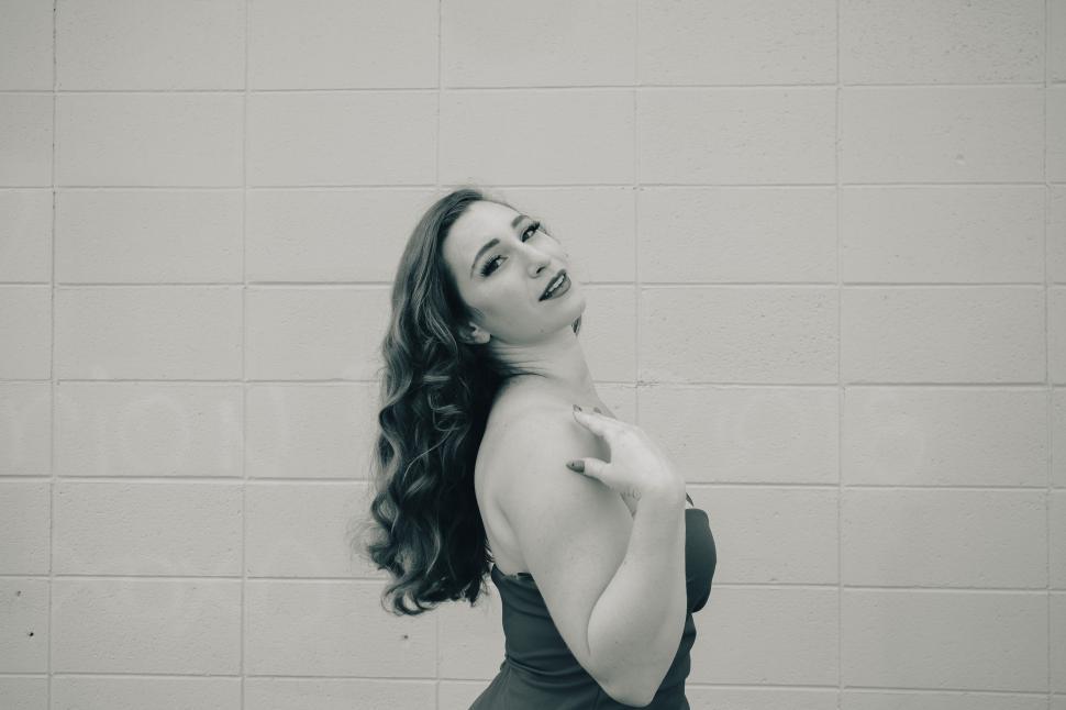 Free Image of Woman poses gracefully against a textured wall, showcasing elegance and confidence 