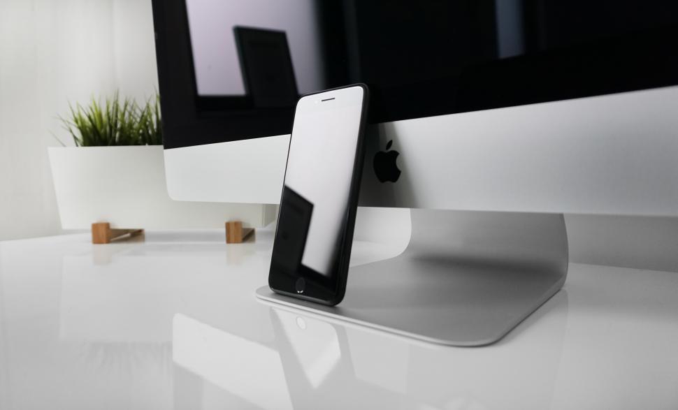 Free Image of Smartphone leaning against modern desktop computer in workspace 