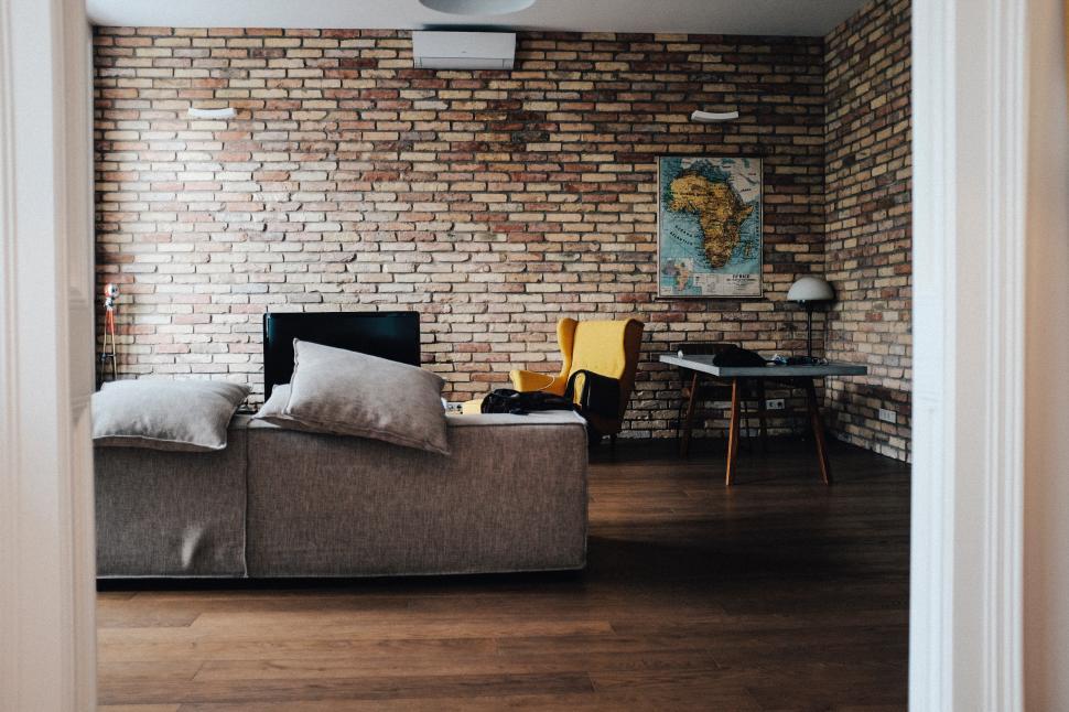 Free Image of Cozy living room with yellow chair and brick wall decor 