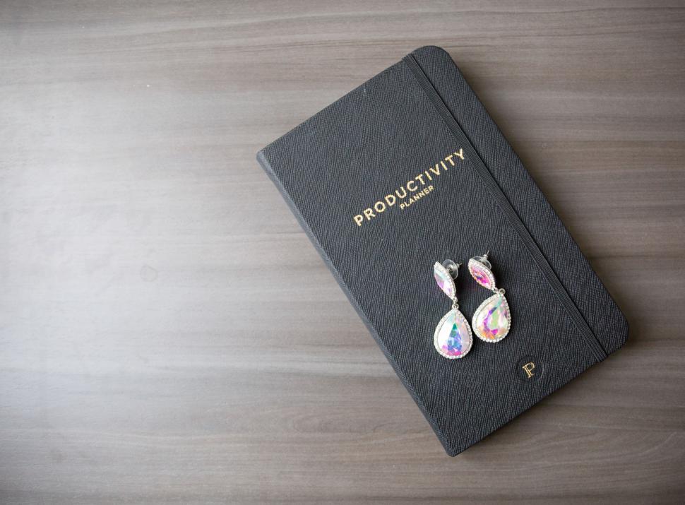 Free Image of Elegant earrings next to a productivity planner on a table 