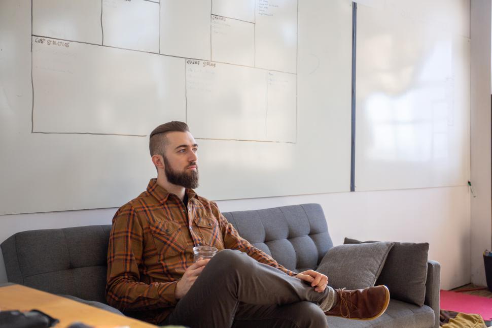 Free Image of Man sitting on couch in office during work hours 