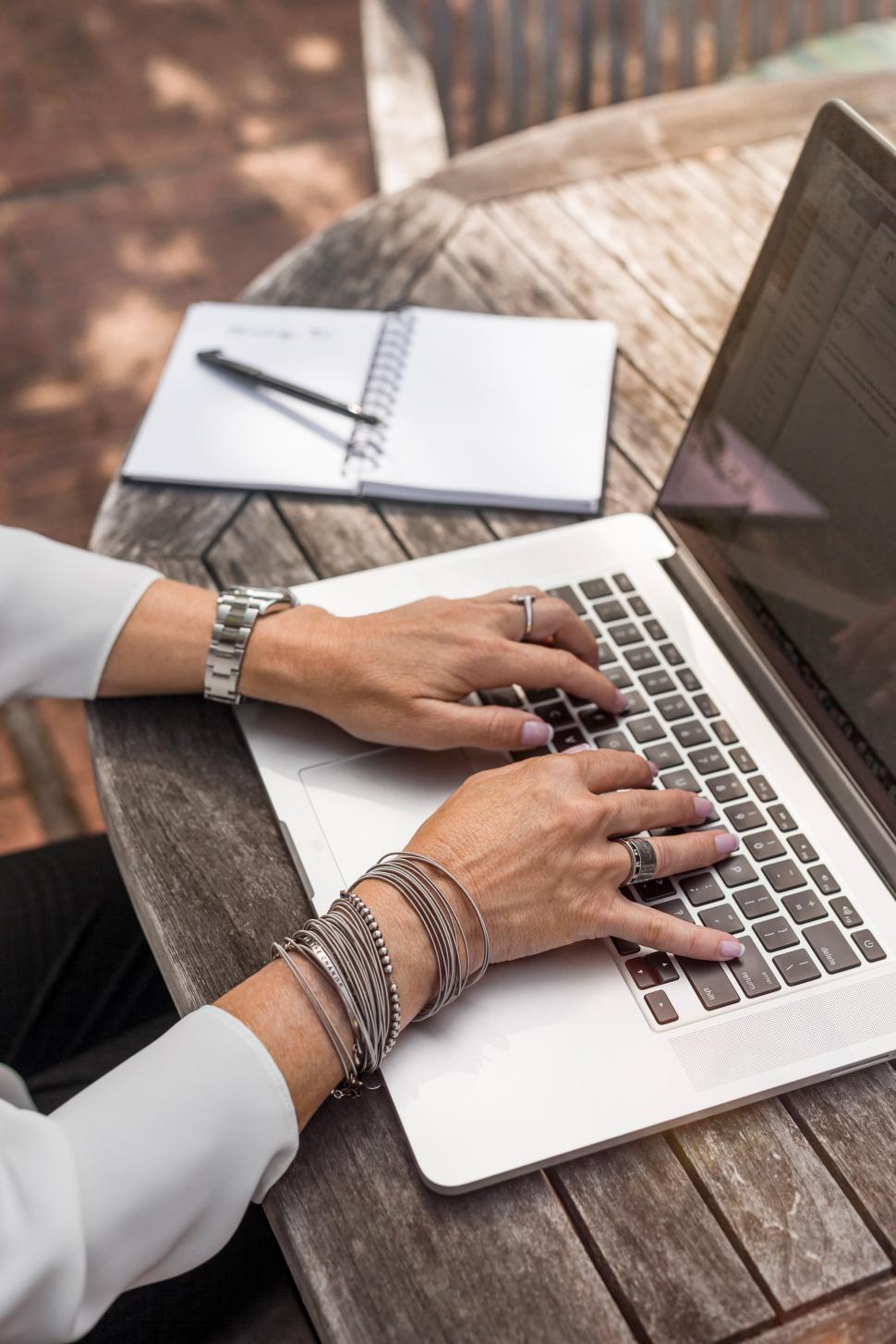 Free Image of Woman working on laptop at outdoor table in daylight 