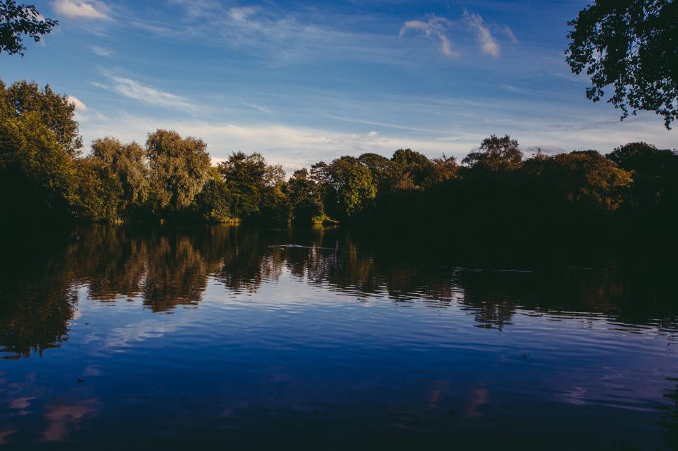 Free Image of Calm river reflecting trees under a clear blue sky 