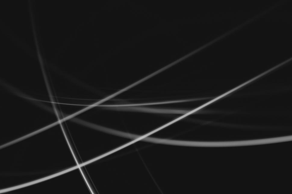 Free Image of Light trails create abstract patterns in dark background 