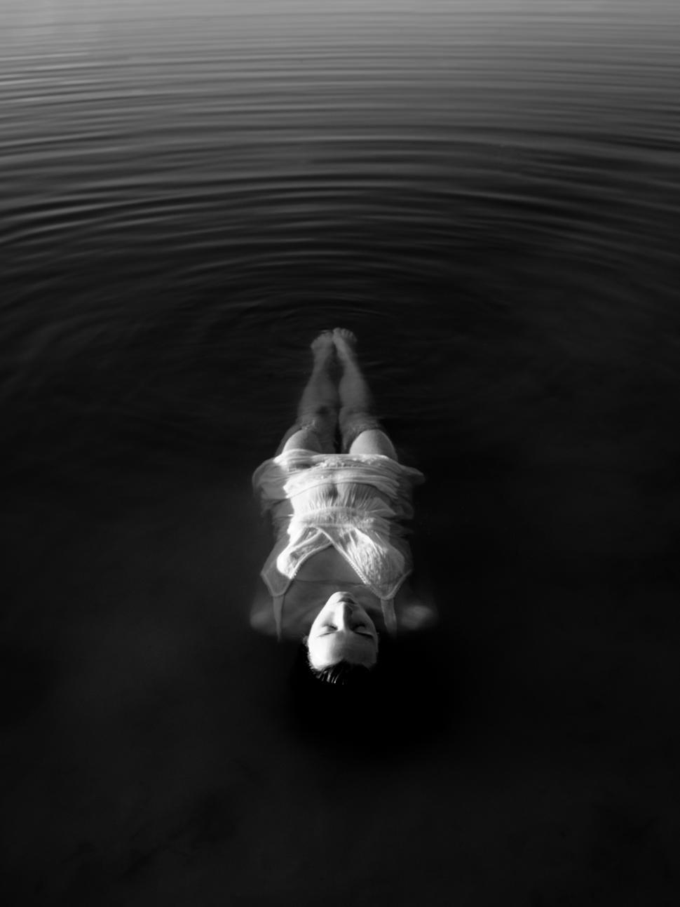 Free Image of Woman floating peacefully in calm water during twilight hours 