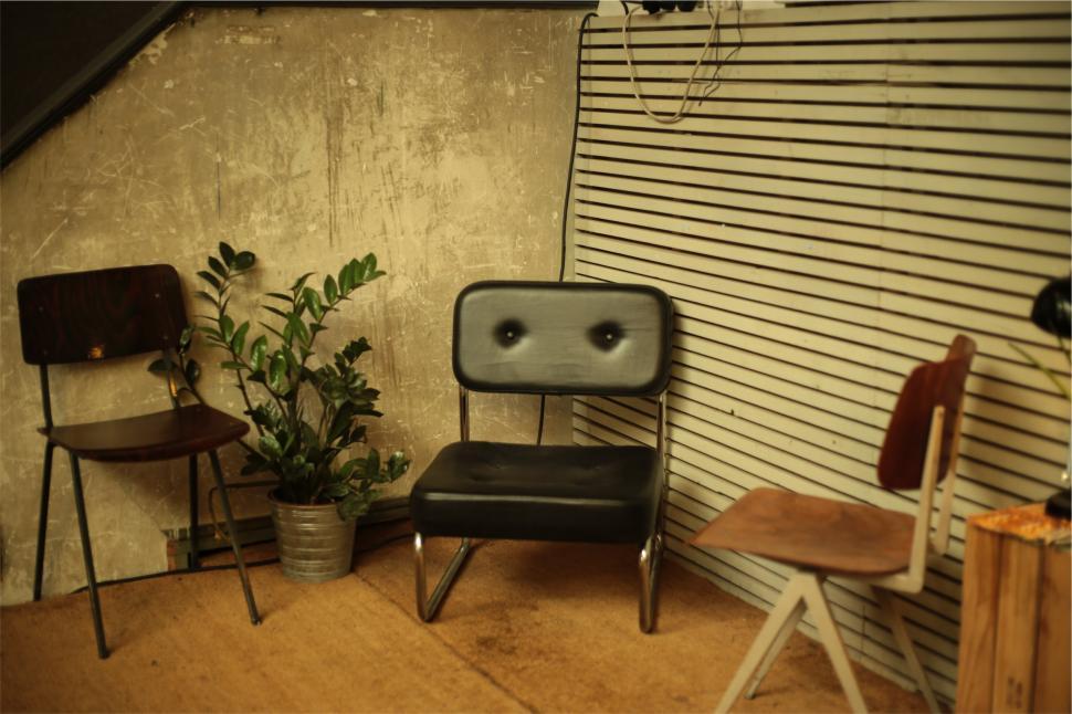 Free Image of Chairs arranged in a cozy corner with plant and striped wall in a creative space 