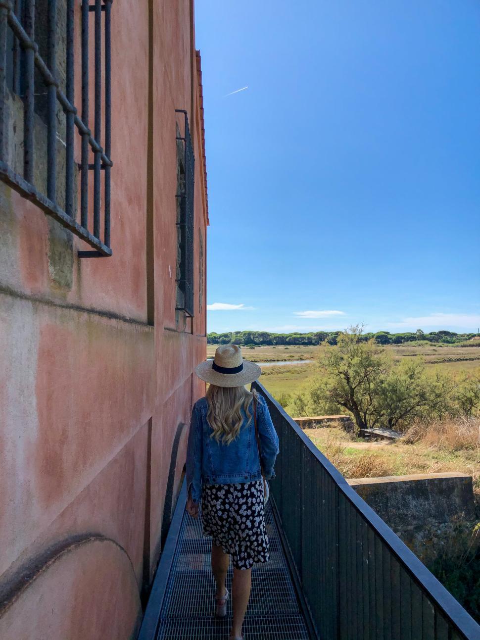 Free Image of Woman walking along a pathway beside a historical building 