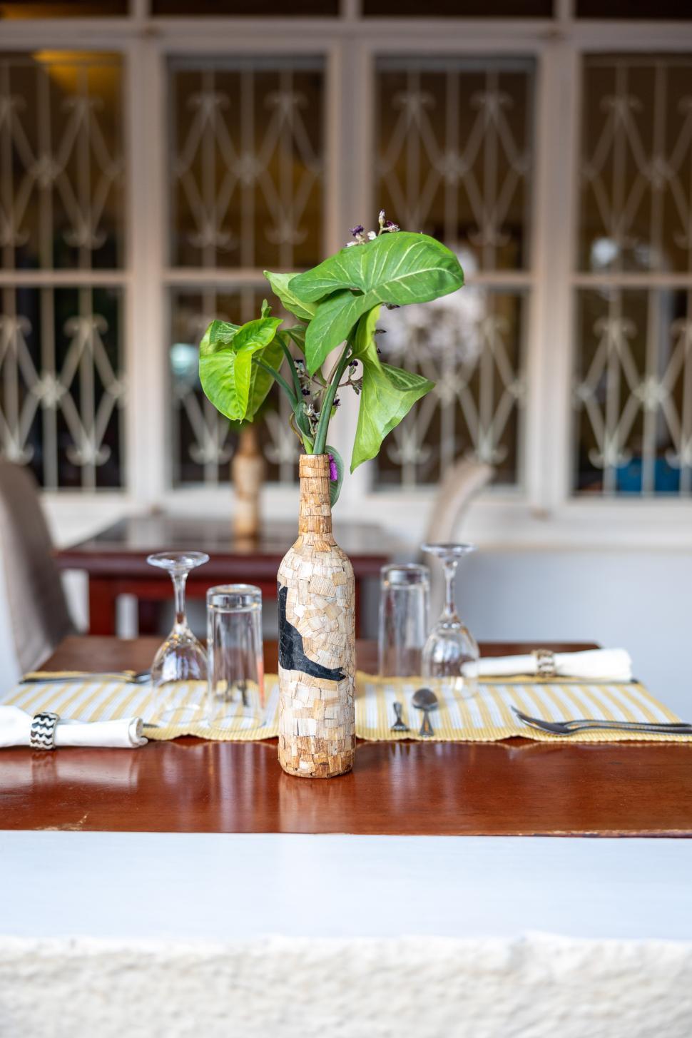 Free Image of Unique bottle vase with greenery on a dining table in a restaurant 