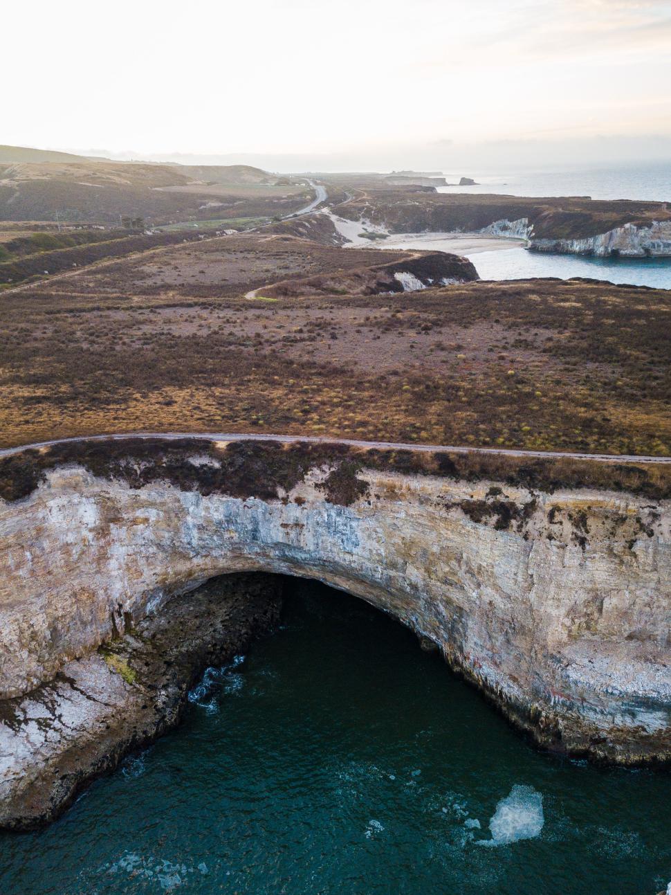 Free Image of Stunning coastal landscape with arch and rugged cliffs at sunset 
