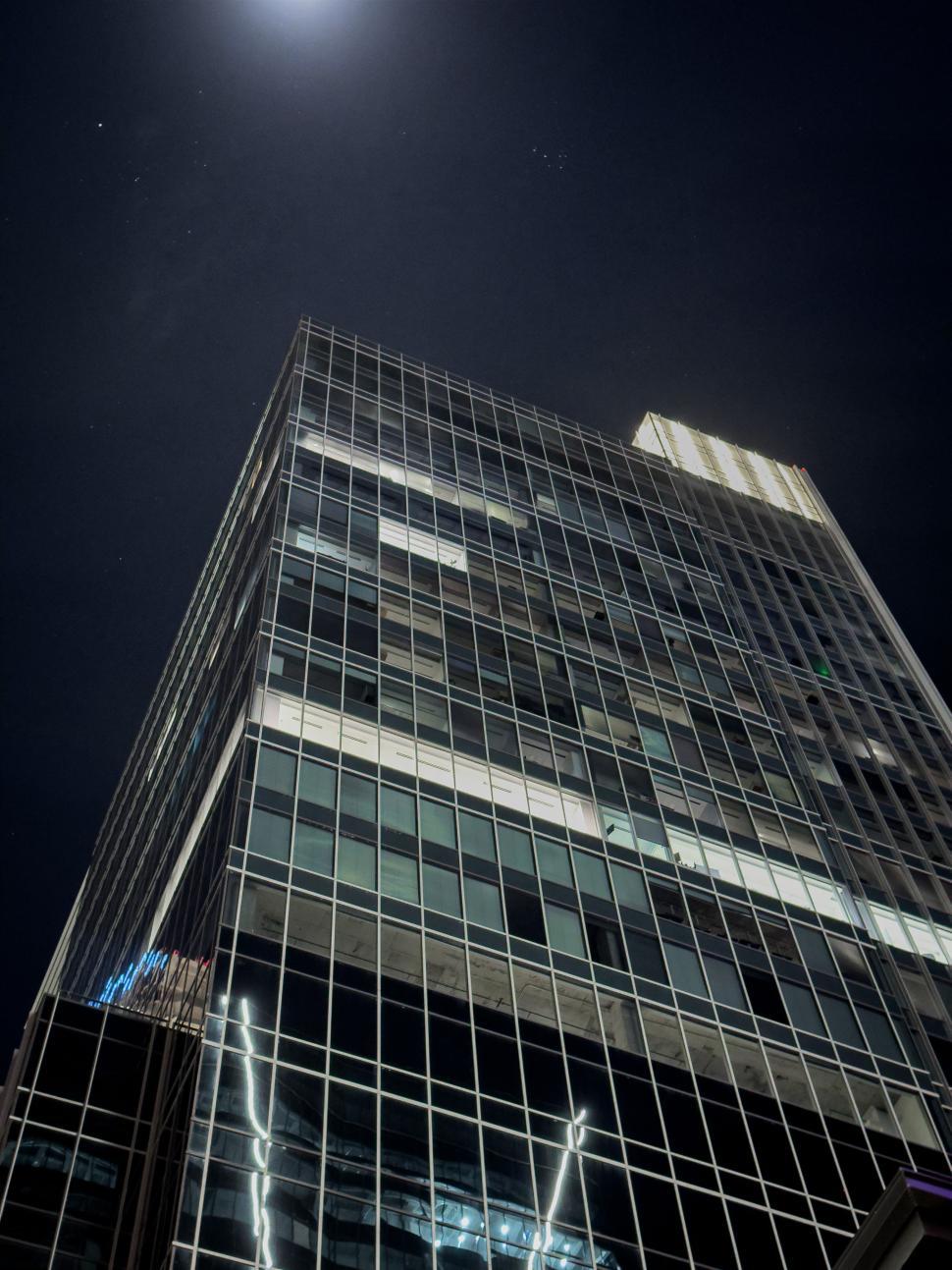 Free Image of Skyscraper illuminated at night under a bright full moon 