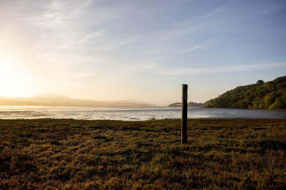 Free Image of Beautiful sunset over the tranquil lake with a wooden post 