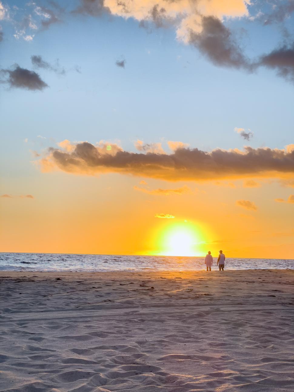 Free Image of Couple strolling along sandy beach during sunset 