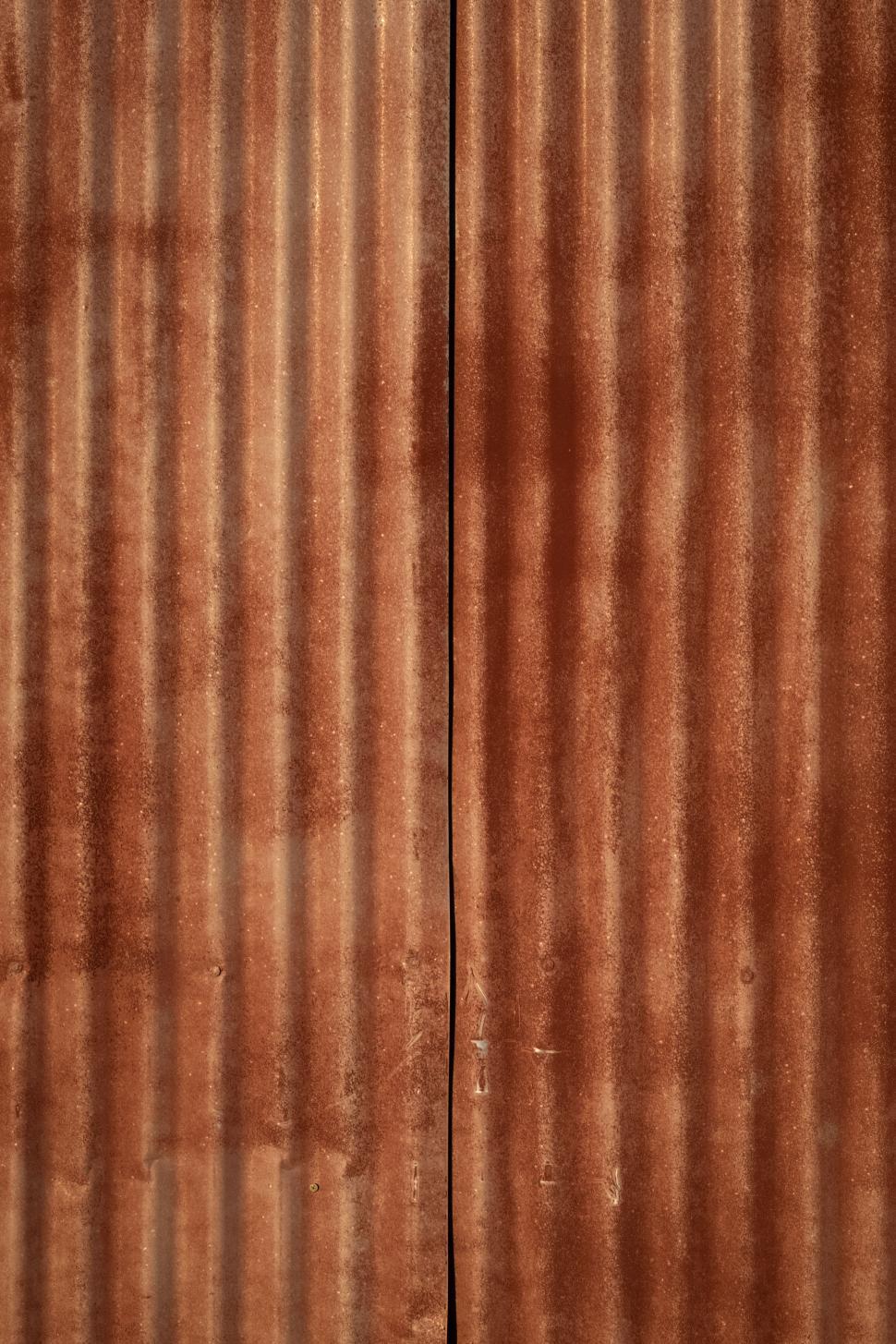 Free Image of Textured brown metal sheets create a rustic background in sunlight 