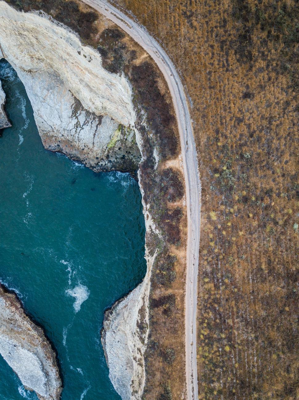 Free Image of River curves alongside rocky cliffs in a remote landscape 