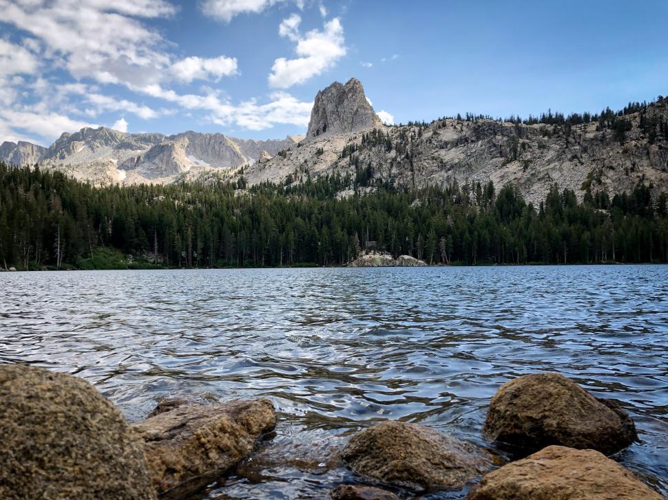 Free Image of Scenic lake view with rocky shoreline and mountainous backdrop 