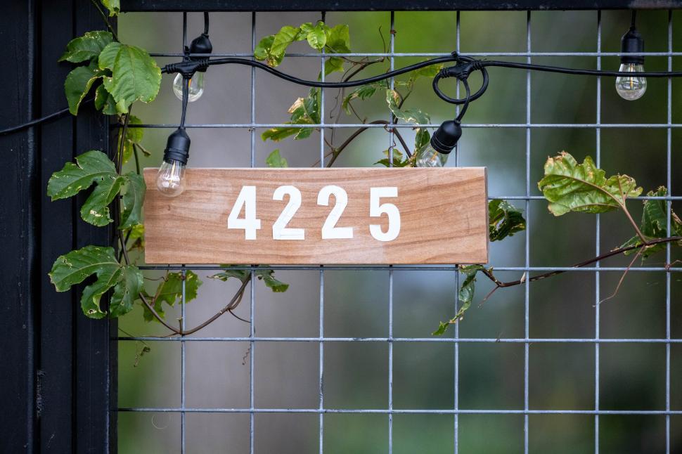 Free Image of House number displayed with greenery and string lights at entrance 
