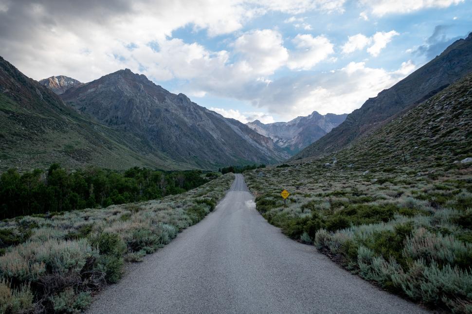 Free Image of Scenic mountain road surrounded by green valleys and mountains 