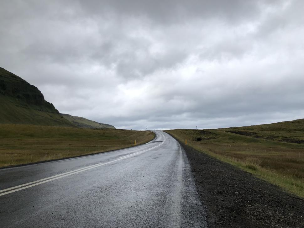 Free Image of Road stretching through a quiet landscape under cloudy skies 