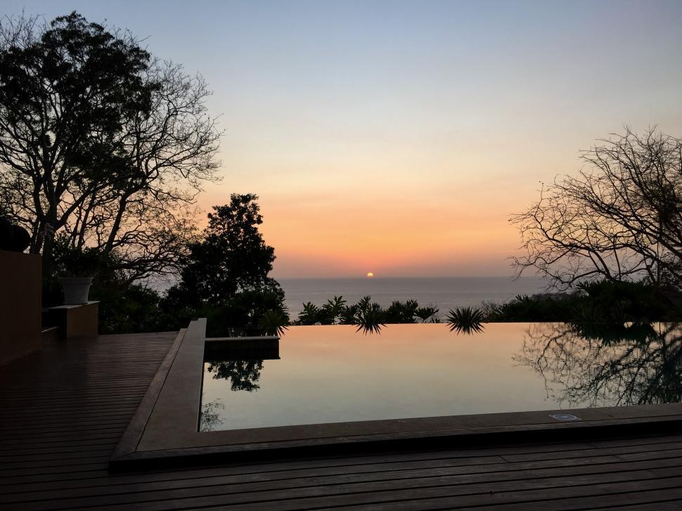 Free Image of Stunning sunset reflecting in still pool with surrounding nature 