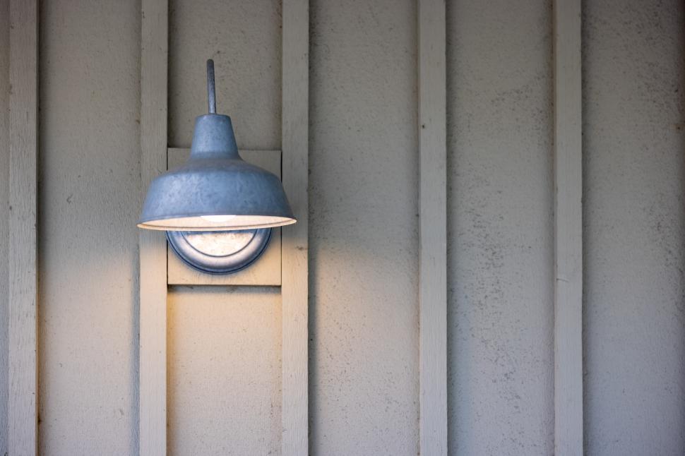 Free Image of Metal wall light illuminating wooden paneling at dusk 