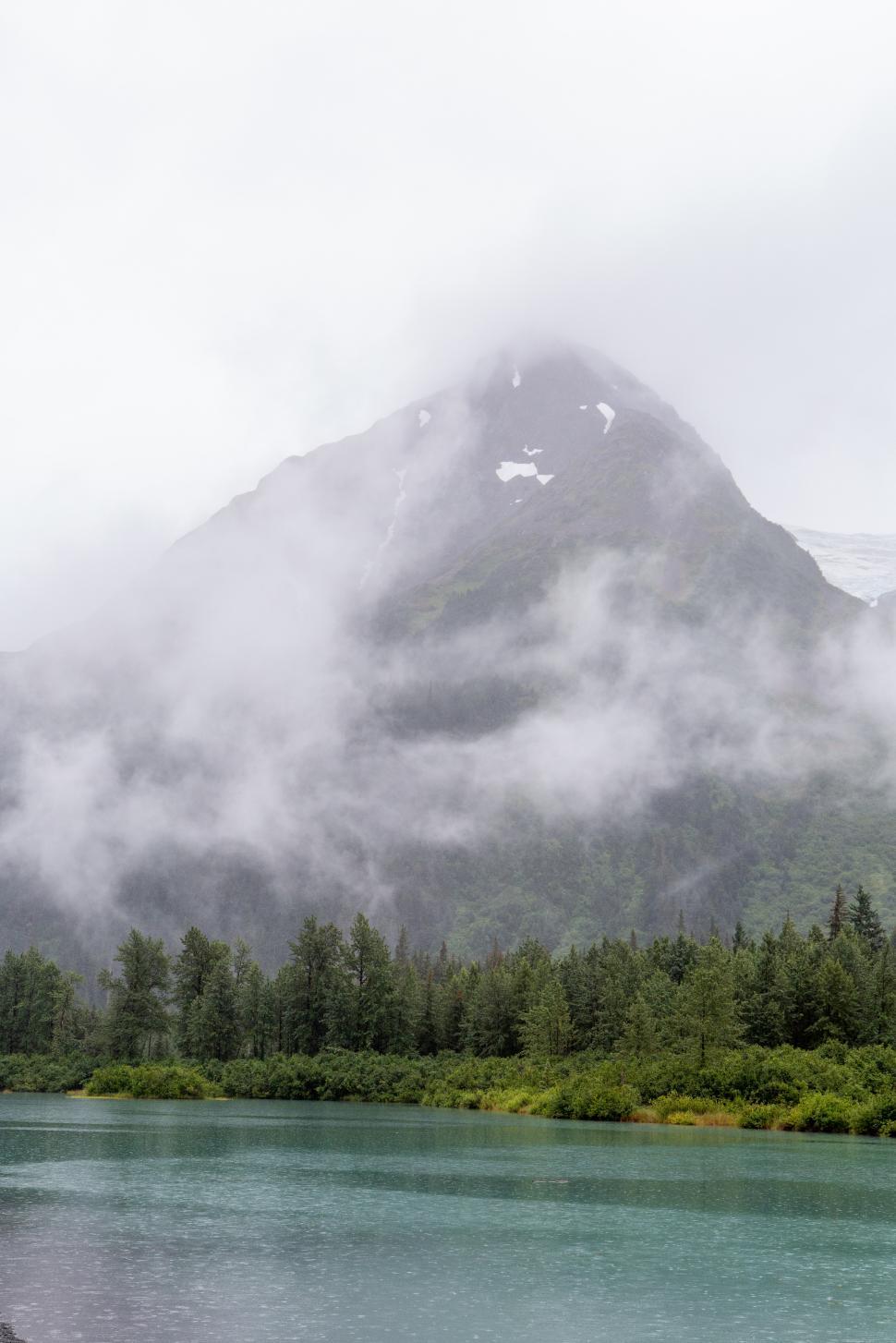 Free Image of Mountain shrouded in mist near tranquil lake in remote wilderness 