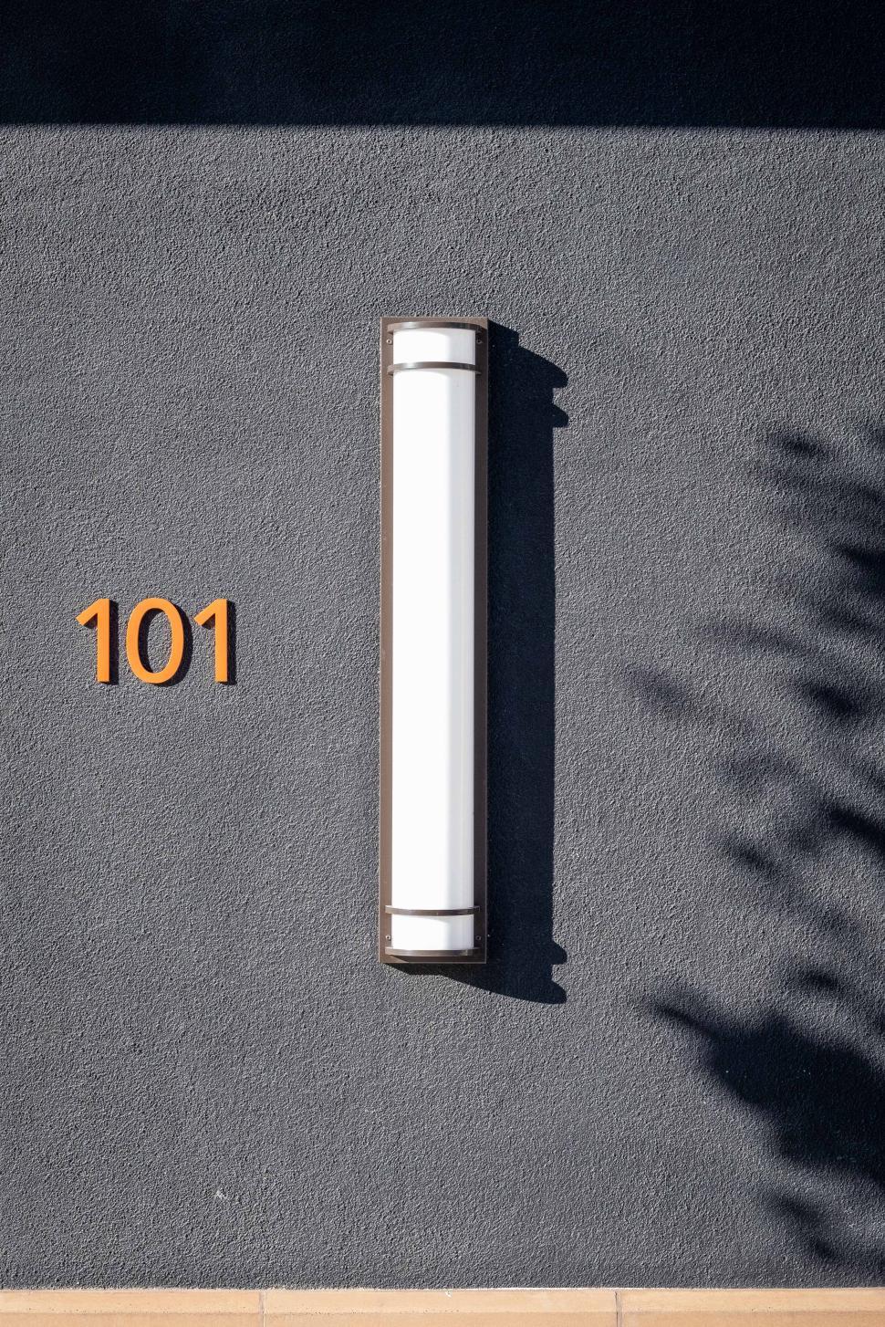 Free Image of Modern light fixture mounted on a textured wall with number display 