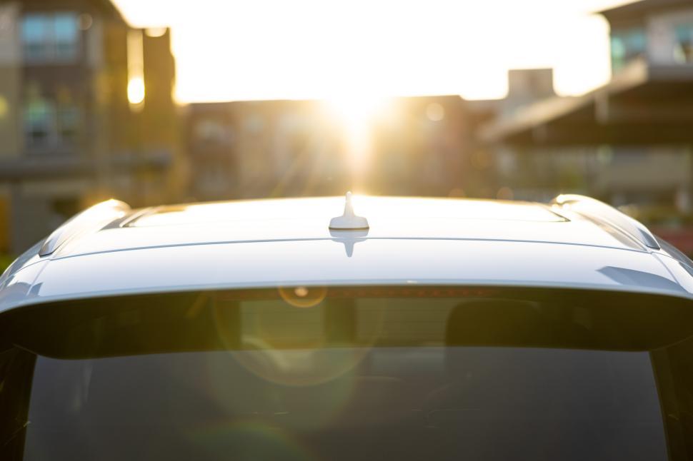 Free Image of Sunlight reflects off car roof during evening in residential area 