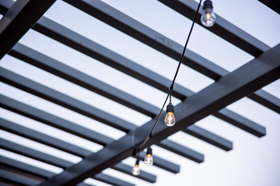 Free Image of String lights hanging from a wooden pergola during twilight hours 