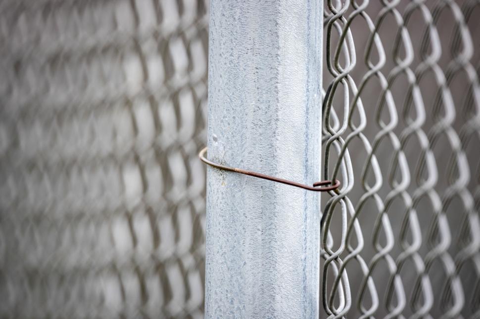 Free Image of Wire securing chain link fence near urban setting 