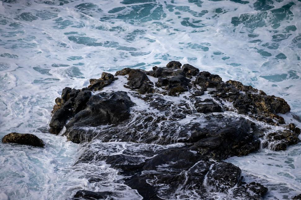 Free Image of Waves crashing against rocks in a coastal setting during daytime 