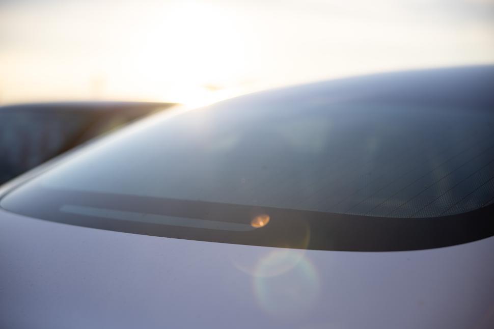 Free Image of Modern vehicle window with sunlight reflecting in a parking lot 