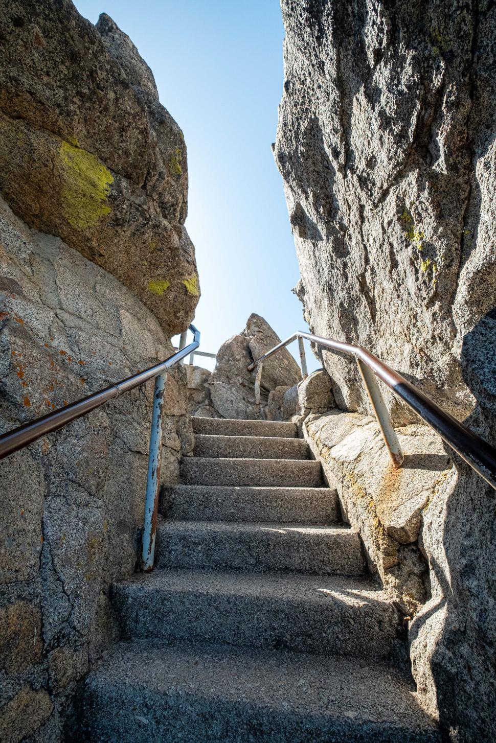 Free Image of Stairway through rocky terrain leads to bright sky above 