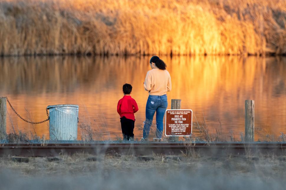 Free Image of Mother and child enjoy peaceful moment by the water at sunset 