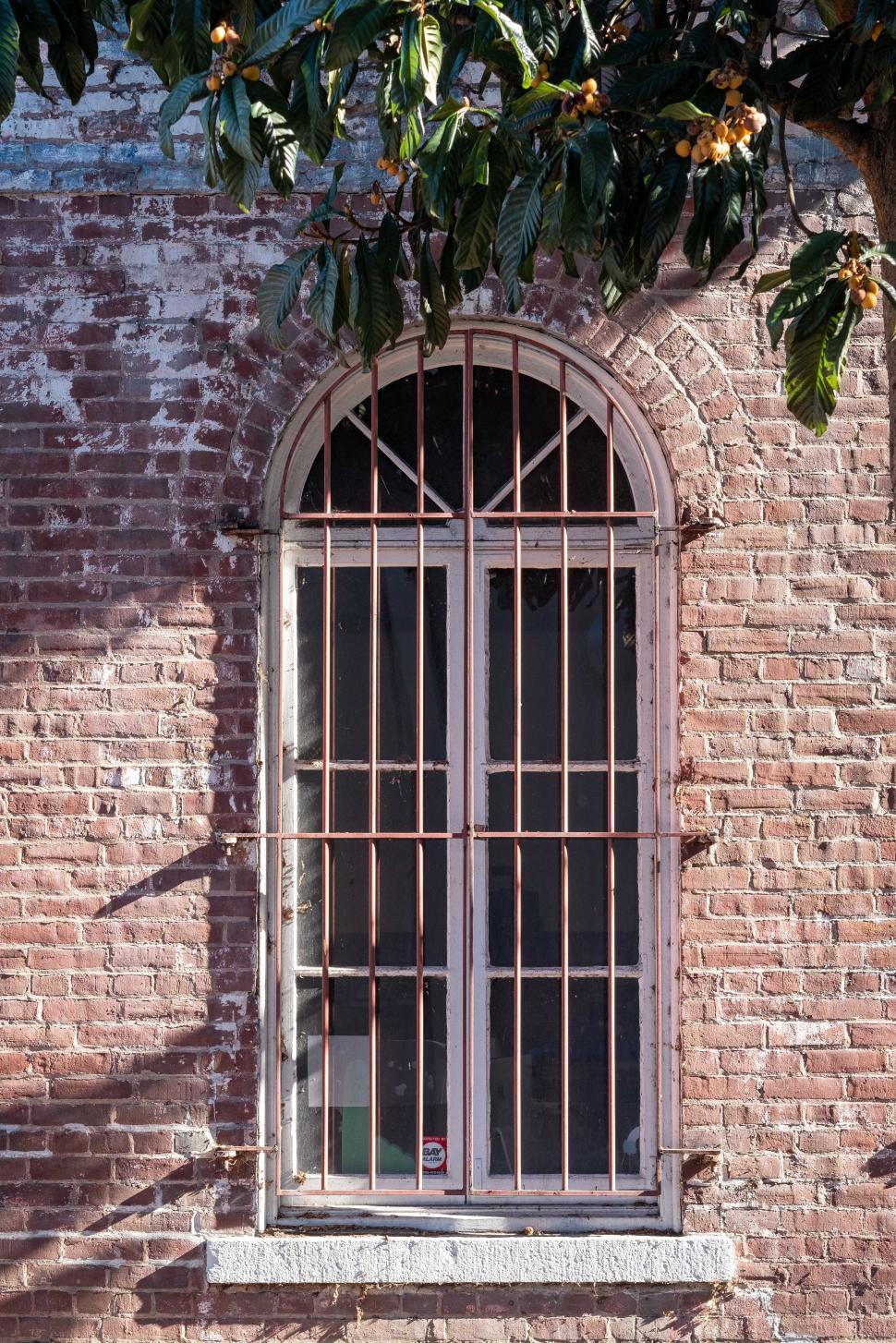 Free Image of Old brick wall with barred window in urban setting during daylight 