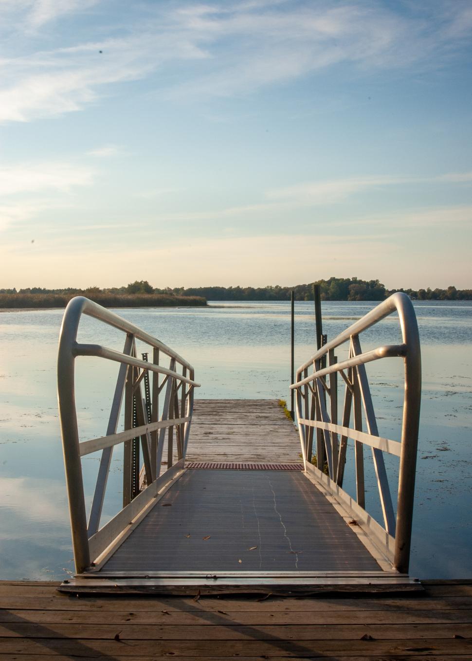 Free Image of Calm wooden dock leading to a serene lake under clear skies 