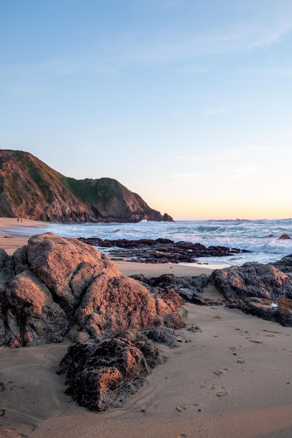 Free Image of Beautiful rocky beach at sunset with gentle waves lapping shore 