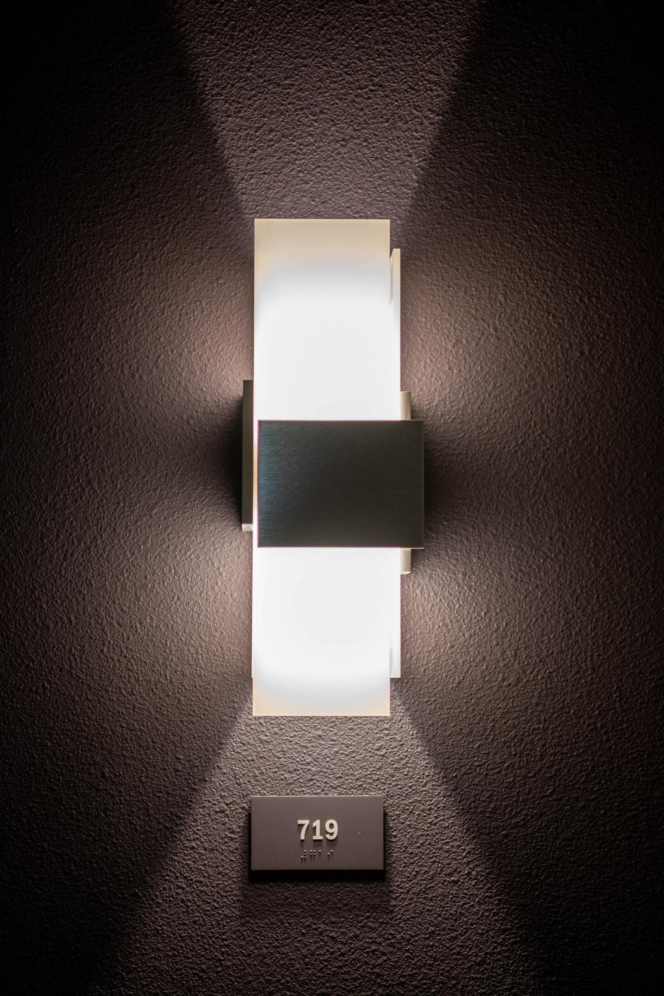 Free Image of Stylish wall sconce illuminated in a modern hallway at night 