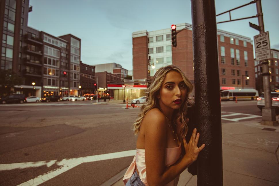 Free Image of Young woman poses by streetlight in urban evening setting 