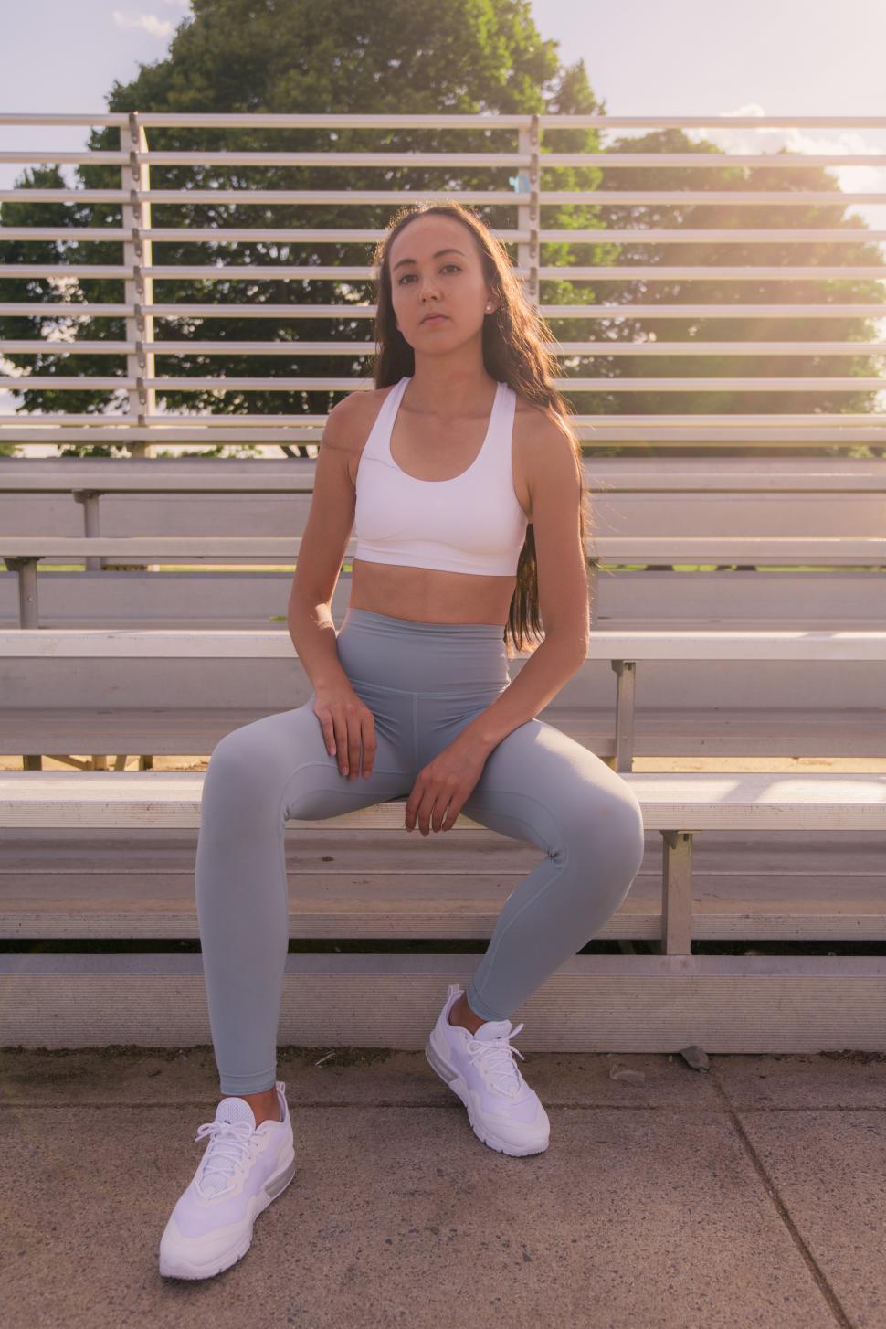 Free Image of Young woman posing confidently on sports bleachers at sunset 